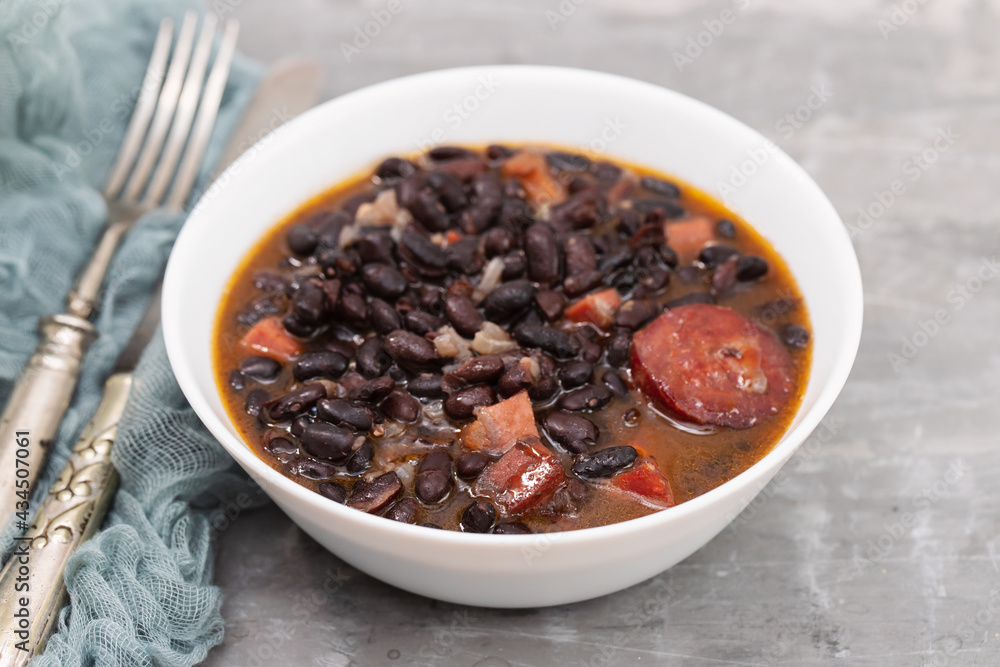 black beans with meat and sausages in white bowl black beans with meat and sausages in white bowl