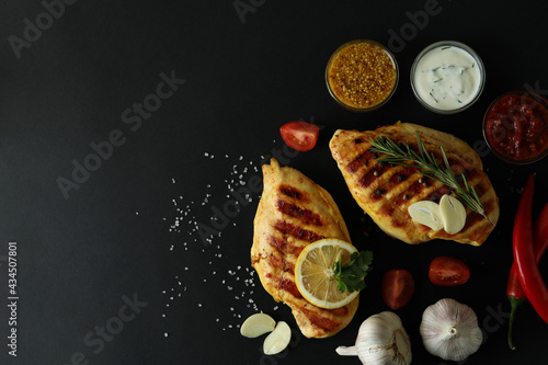 Grilled chicken meat and ingredients on black background, space for text