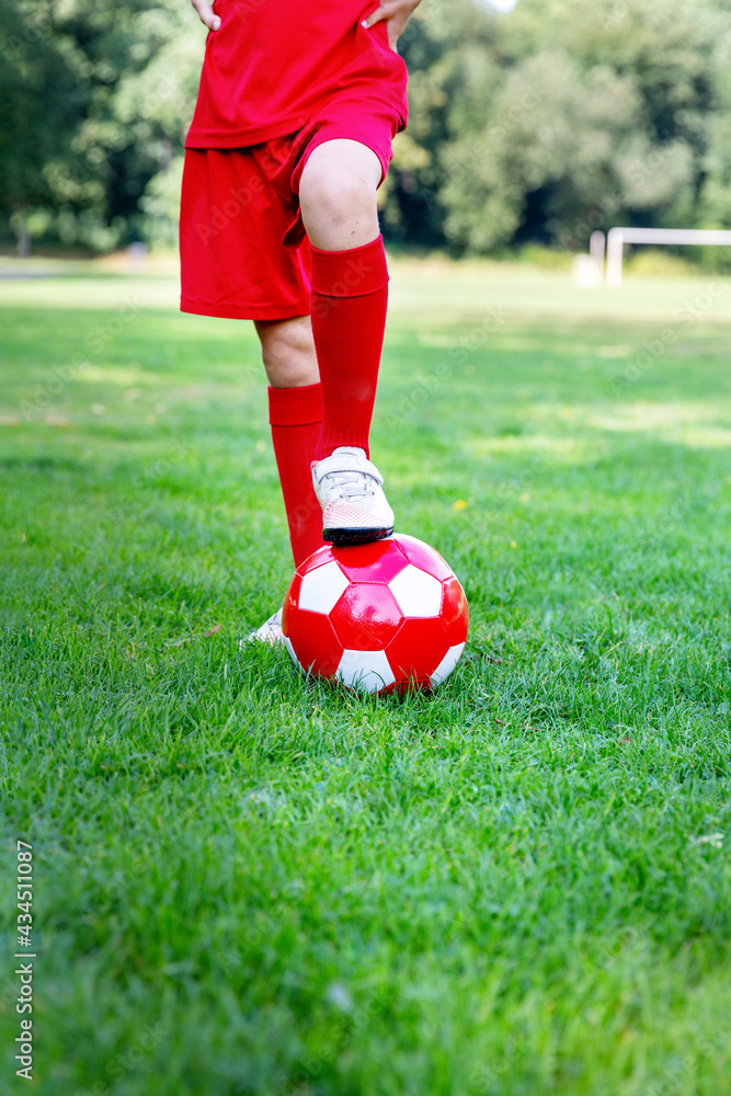 Obraz premium A boy in red gaiters kicks a ball on the football field. Copy Space