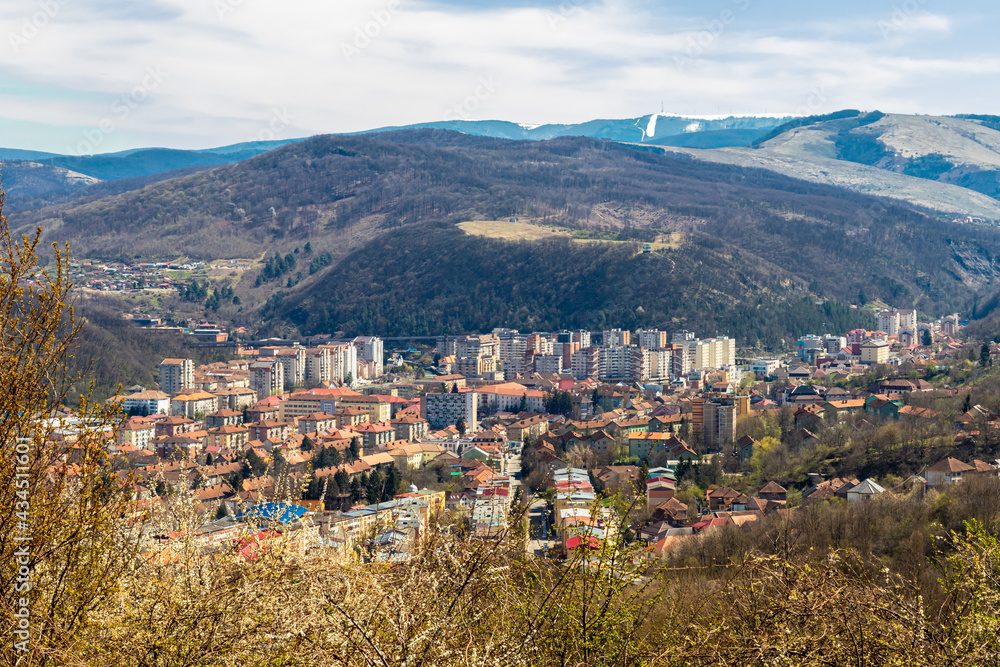 Resita, Romania-April 11, 2021: Top view of the city of Resita, in the middle of spring, when you can still see snow on the mountains surrounding the wonderful city