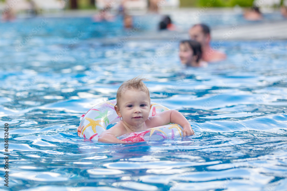 Adorable happy little child, toddler boy, having fun relaxing and playing in a pool in inflatable ring on sunny day during summer vacation Adorable happy little child, toddler boy, having fun relaxing and playing in a pool in inflatable ring on sunny day during summer vacation