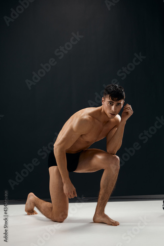 athletic man in dark panties with naked muscular body is kneeling