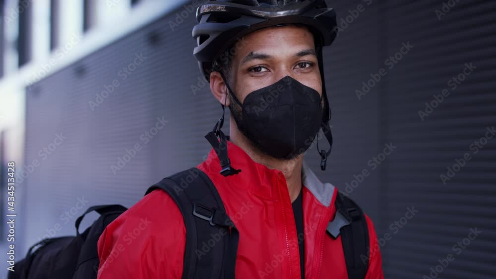 Young courier delivering a food on bike, looking at camera. Coronavirus concept. Young courier delivering a food on bike, looking at camera. Coronavirus concept.