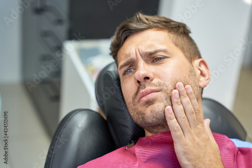 Brunette man suffering from dental pain in clinic