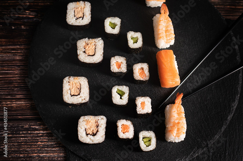 Sushi sind aufgelegt auf der schwarzen Platte Schwarze Stäbe fassen ein Sushi an. Sehr gut geeignet für chinesischen Restaurant, Querformat, Asia Küche