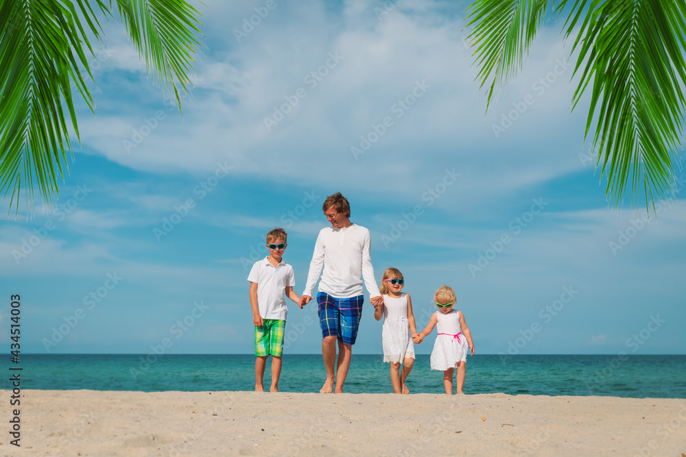 happy father and three kids walking on beach