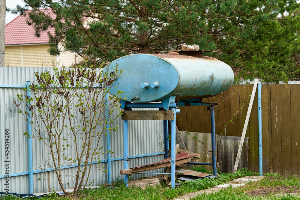 Blue metal tank for storing water at a summer cottage Blue metal tank for storing water at a summer cottage