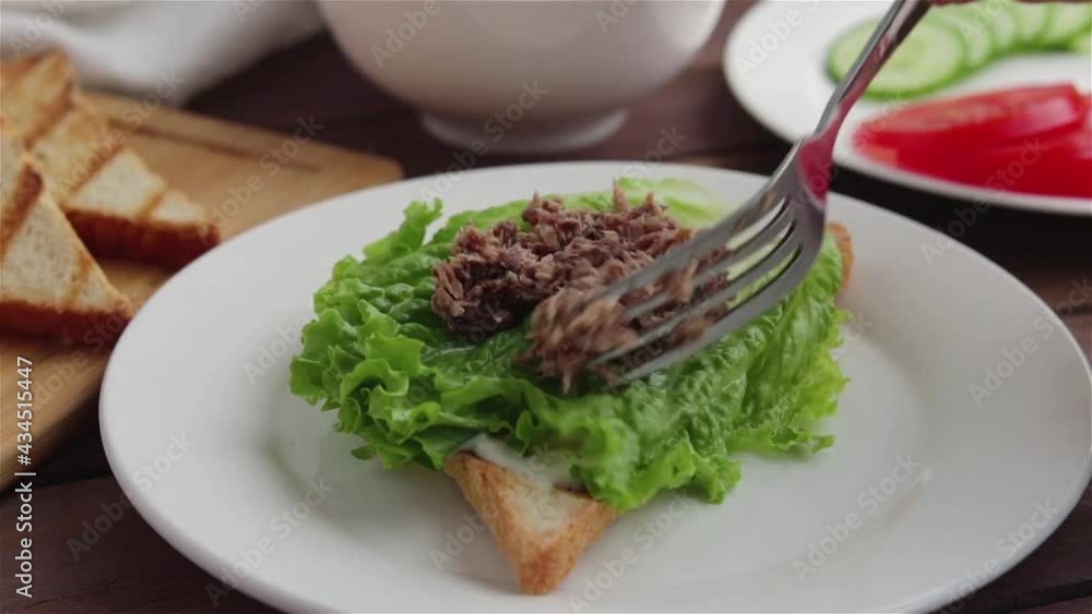 hand with fork places canned tuna on lettuce bread prepare healthy sandwich hand with fork places canned tuna on lettuce bread prepare healthy sandwich