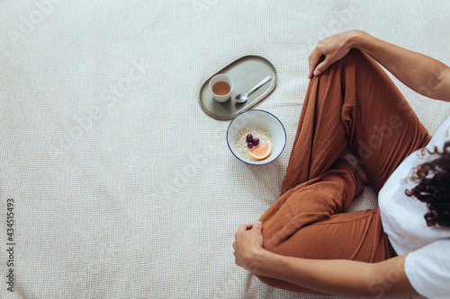 Frau im Schneidersitz mit Tee und Frühstück im Bett
