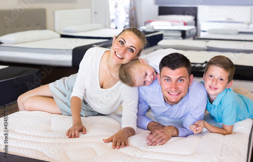 Man with wife and children are testing quality of mattress in store.
