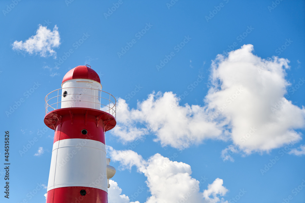 Lighthouse in red and white in front of sky with clouds Lighthouse in red and white in front of sky with clouds