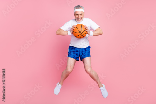 Fototapeta Naklejka Na Ścianę i Meble -  Full length body size photo senior man jumping up playing basketball throwing ball cheerful happy isolated pastel pink color background