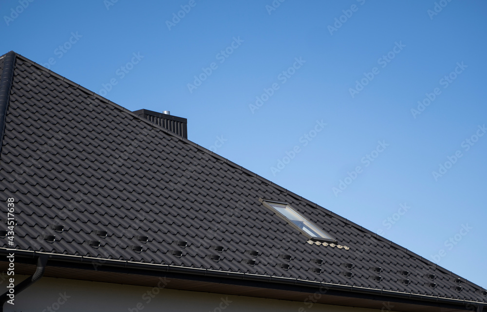 Brown corrugated metal profile roof installed on a modern house. The roof of corrugated sheet. Roofing of metal profile wavy shape. Modern roof made of metal. Metal roofing.