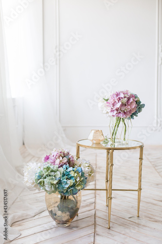 Tender simple  interior in light colors with tule  bouquets of artificial hydrangea and elegant  mirror table on light parquet floor