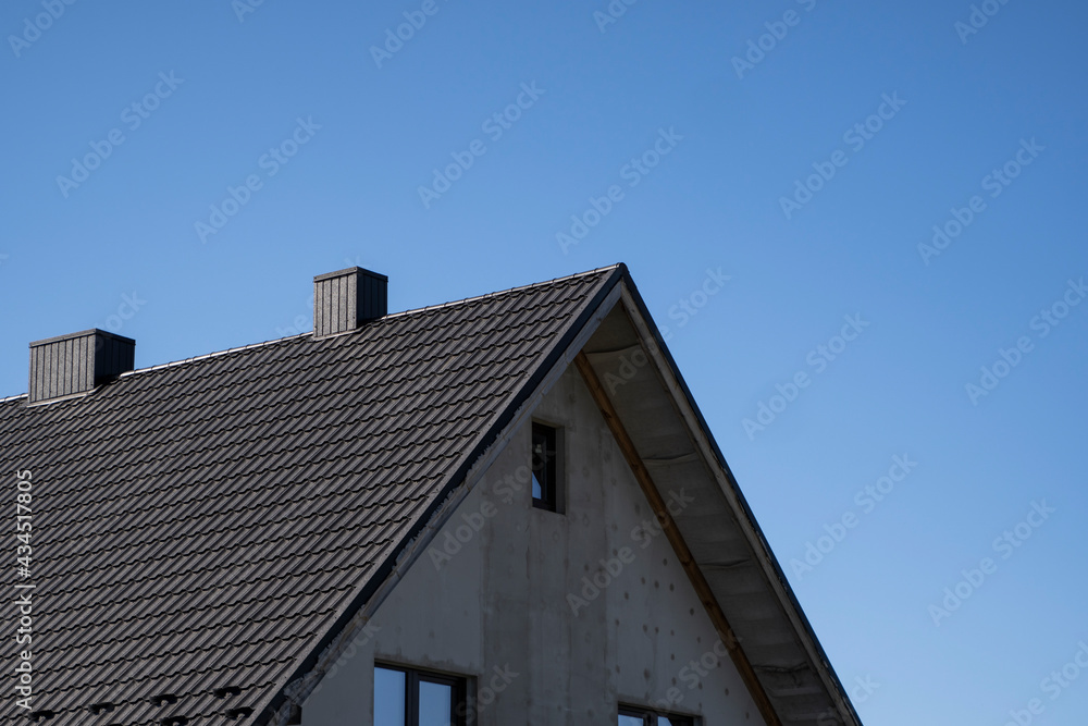 Brown corrugated metal profile roof installed on a modern house. The roof of corrugated sheet. Roofing of metal profile wavy shape. Modern roof made of metal. Metal roofing. Brown corrugated metal profile roof installed on a modern house. The roof of corrugated sheet. Roofing of metal profile wavy shape. Modern roof made of metal. Metal roofing.