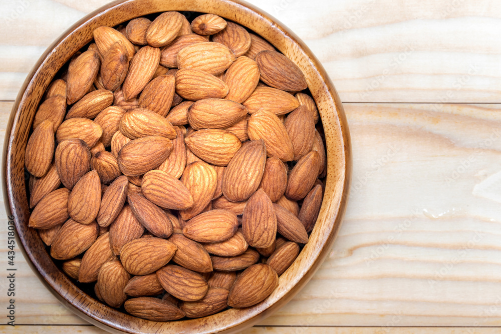 Peeled almond in a wooden bowl on wooden plank. Peeled almond in a wooden bowl on wooden plank.