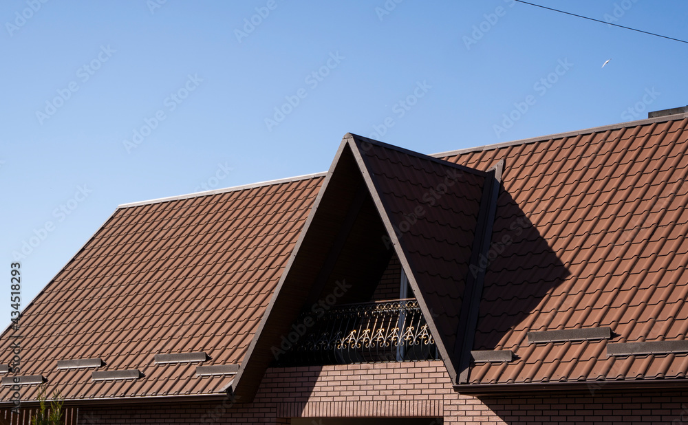 Brown corrugated metal profile roof installed on a modern house. The roof of corrugated sheet. Roofing of metal profile wavy shape. Modern roof made of metal. Metal roofing. Brown corrugated metal profile roof installed on a modern house. The roof of corrugated sheet. Roofing of metal profile wavy shape. Modern roof made of metal. Metal roofing.