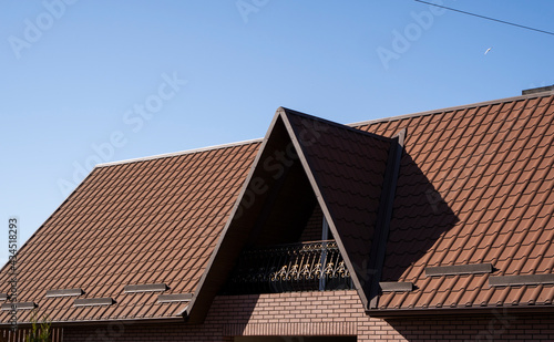 Brown corrugated metal profile roof installed on a modern house. The roof of corrugated sheet. Roofing of metal profile wavy shape. Modern roof made of metal. Metal roofing.