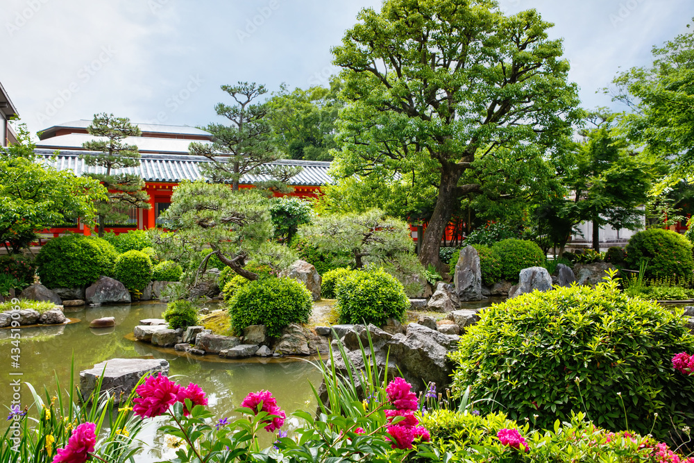Japanese garden in Fushimi Inari Taisha Shrine in Kyoto, Japan with beautiful red gates. Blossoming garden in japanese style.