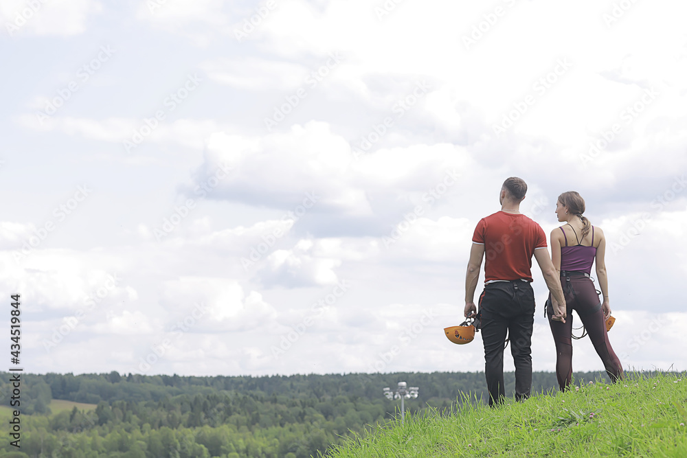 love couple in helmets outdoor activities nature, rope climbing park, against the sky