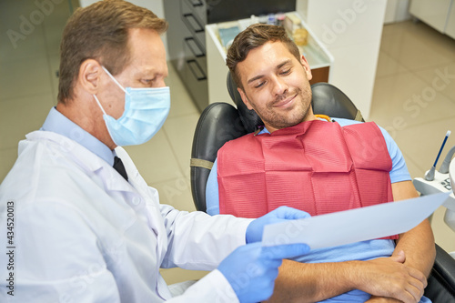 Contented patient and doctor looking at paper at dental clinic