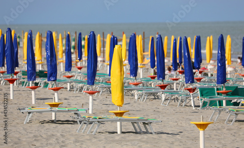 Fototapeta Naklejka Na Ścianę i Meble -  beach with many closed umbrellas with no one on the deck chairs due to the lockdown