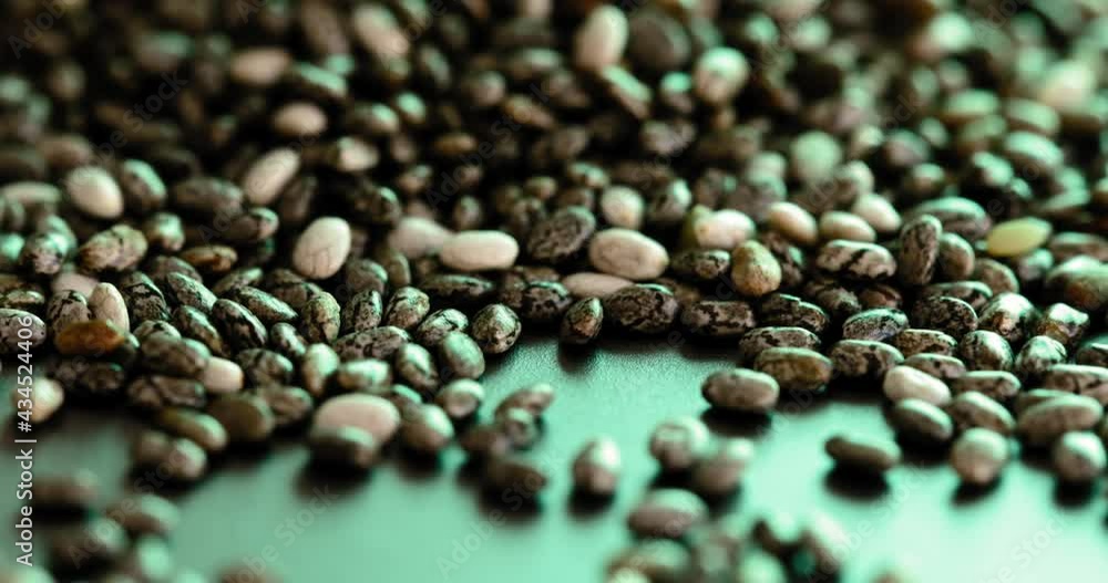Close-up and smoothly shift focus from top to bottom on the chia seeds lying in the green light. This video can be used as a display of the chia crypto coin. High quality 4K footage Close-up and smoothly shift focus from top to bottom on the chia seeds lying in the green light. This video can be used as a display of the chia crypto coin. High quality 4K footage