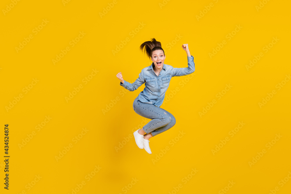 Full length body size photo young pretty girl jumping up gesturing like winner isolated bright yellow color background