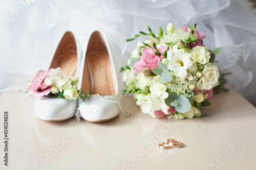 Wedding classic accessories: Bride's beige shoes, rings, boutonniere and wedding bouquet. Bridal accessories