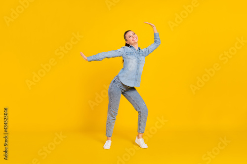 Full length photo of funny charming young woman wear denim shirt smiling dancing isolated yellow color background