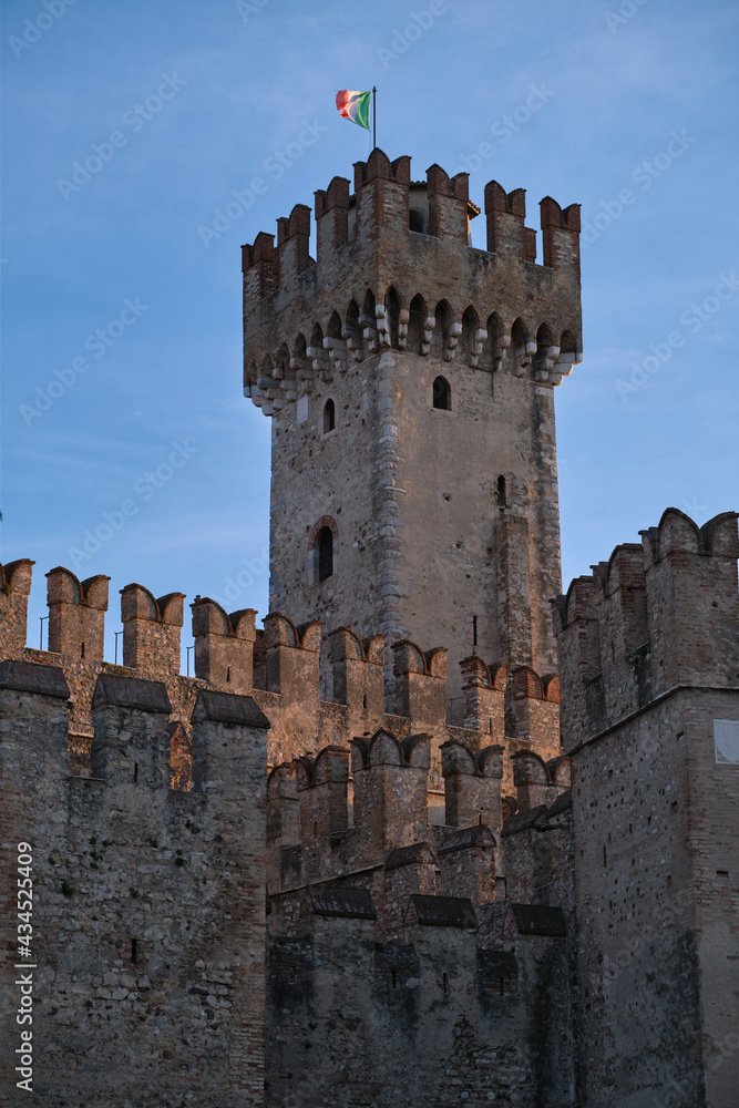Sirmione Castle, Italy. Close-up of an ancient castle in Italy. Italian flag at the castle of Sirmione. Historic castle wall on the water. Fortress on the water. Castle tower.