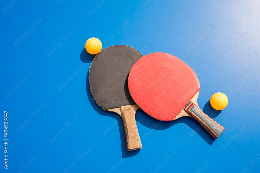 Blue table tennis or ping pong. Outdoor tablet tennis. Close-up ping-pong. Accessories for table tennis racket and ball on a blue tennis table. Sport. Blue table tennis or ping pong. Outdoor tablet tennis. Close-up ping-pong. Accessories for table tennis racket and ball on a blue tennis table. Sport.