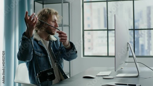 Blond freelance worker in denim jacket puts on photo camera photo