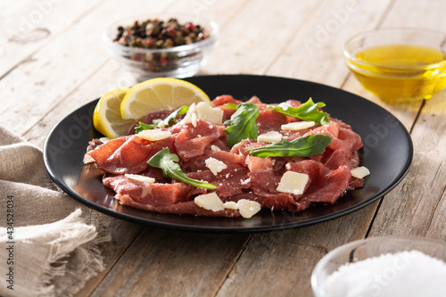 Marbled beef carpaccio on black plate on rustic wooden table