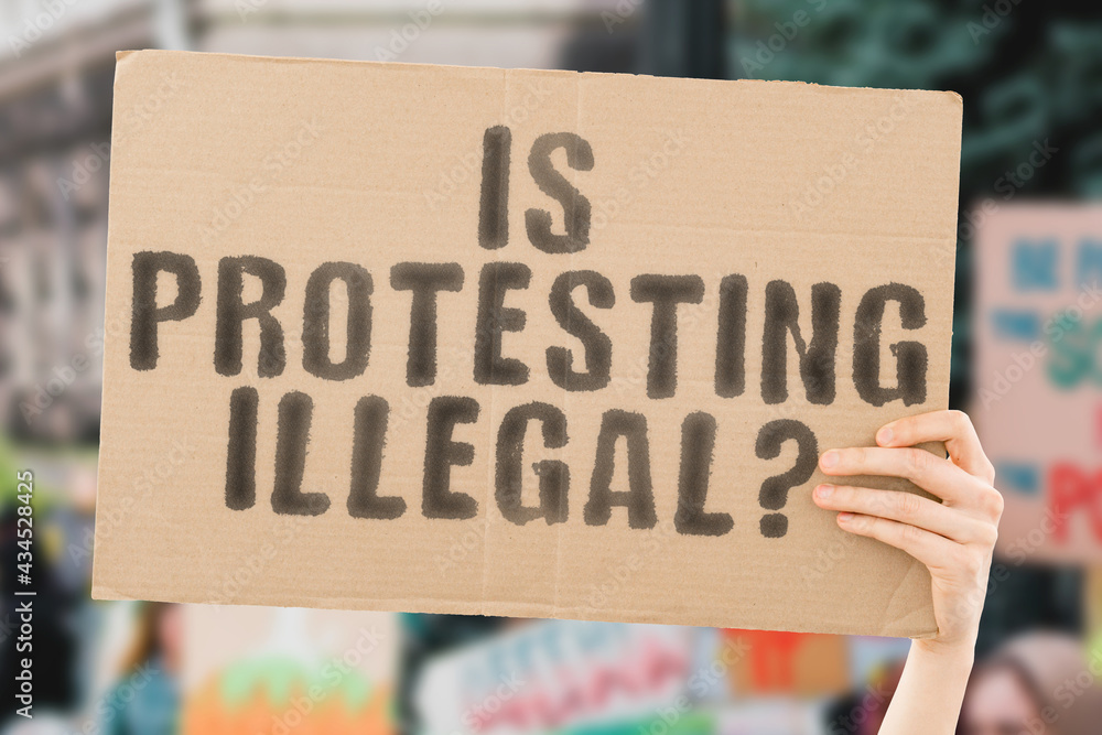 The question " Is protesting illegal? " on a banner in men's hand