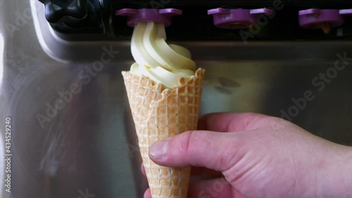 The process of filling waffle cone with ice cream. Man making ice cream