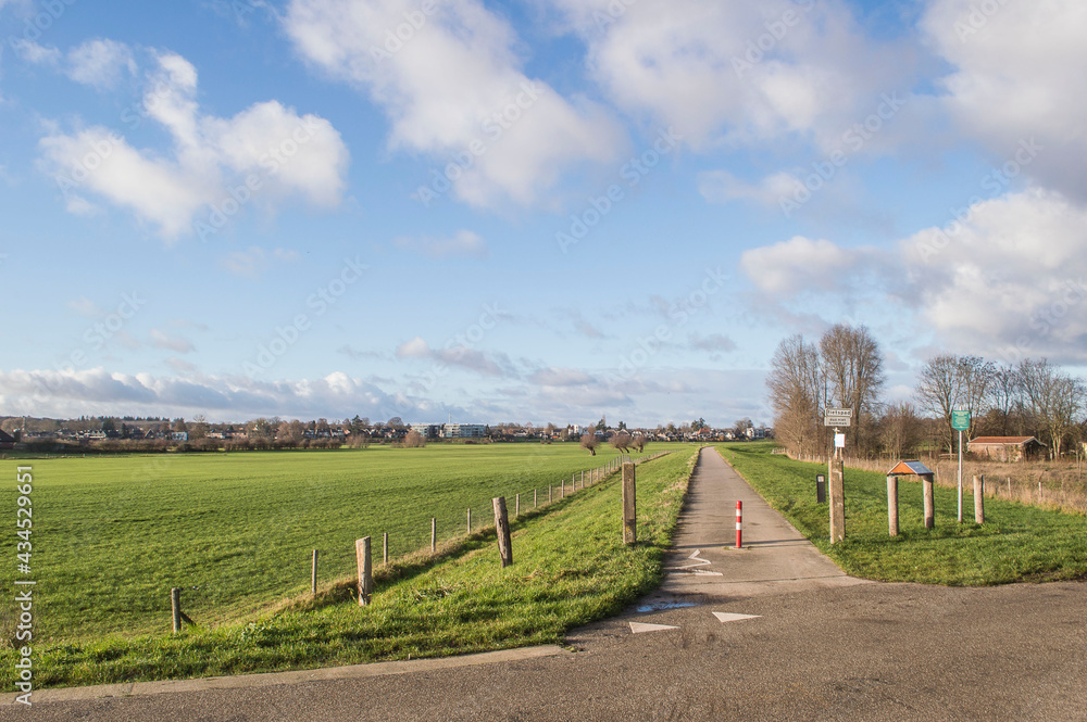 biking road on dike near river IJssel in Dutch polder in winter