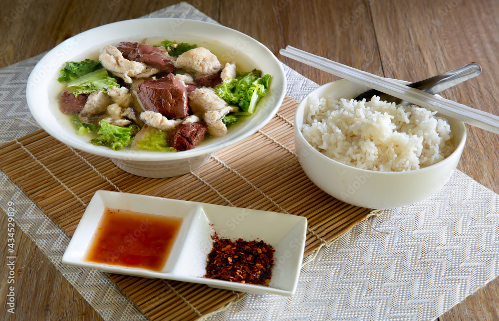 Boiled soup blood pork in bowl and flavouring in white bowl on bamboo mat, Boiled soup blood pork in bowl and flavouring in white bowl on bamboo mat,