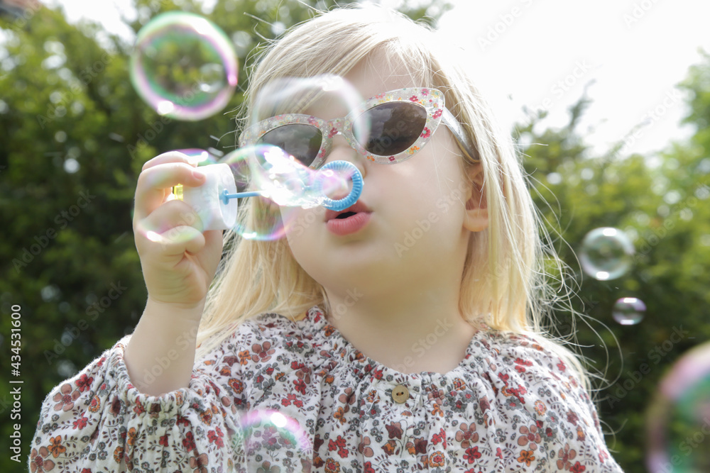 Portrait of fashionable toddler girl blowing soap bubbles in park. Portrait of fashionable toddler girl blowing soap bubbles in park.