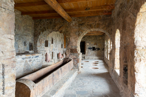 Old wine cellar in ancient Nekresi monastery with qvevris buried in stone floor and wooden trough for trampling grapes, Georgia