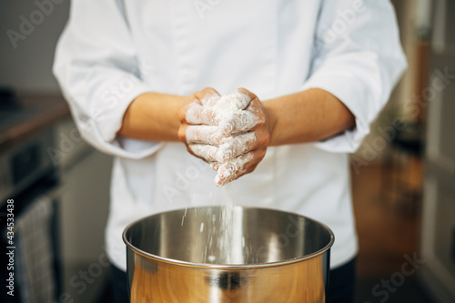 Professional pastry chef in the process of preparing a cake with meringue, in her home kitchen