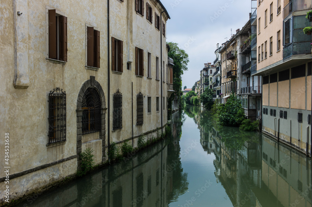 Houses along a canal, mirroring into the water, in Padua in Italy, seen from the Ponte delle Toricelle.