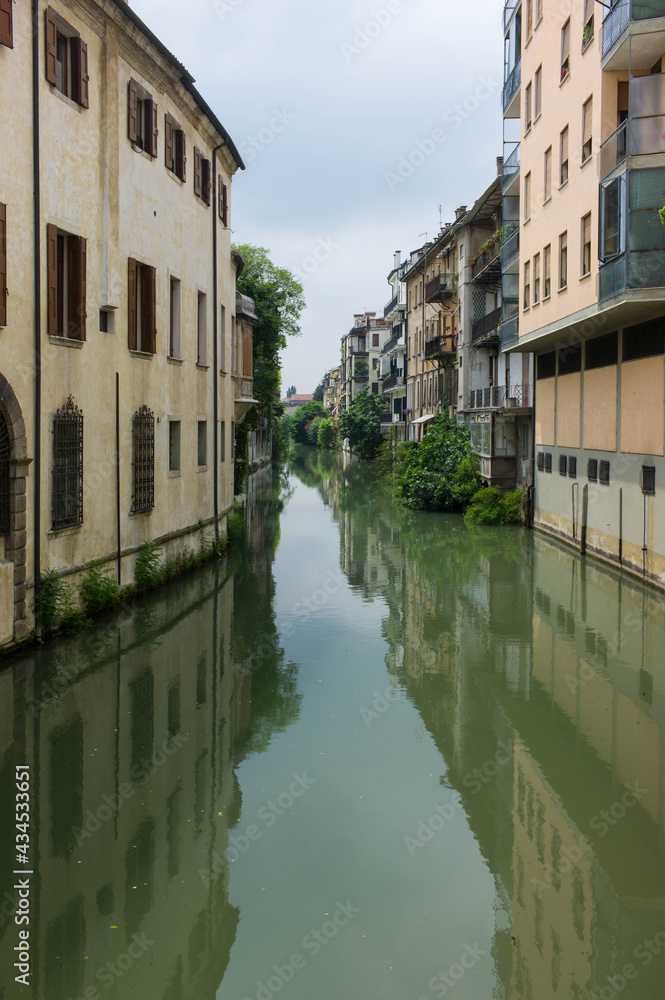 Houses along a canal, mirroring into the water, in Padua in Italy, seen from the Ponte delle Toricelle