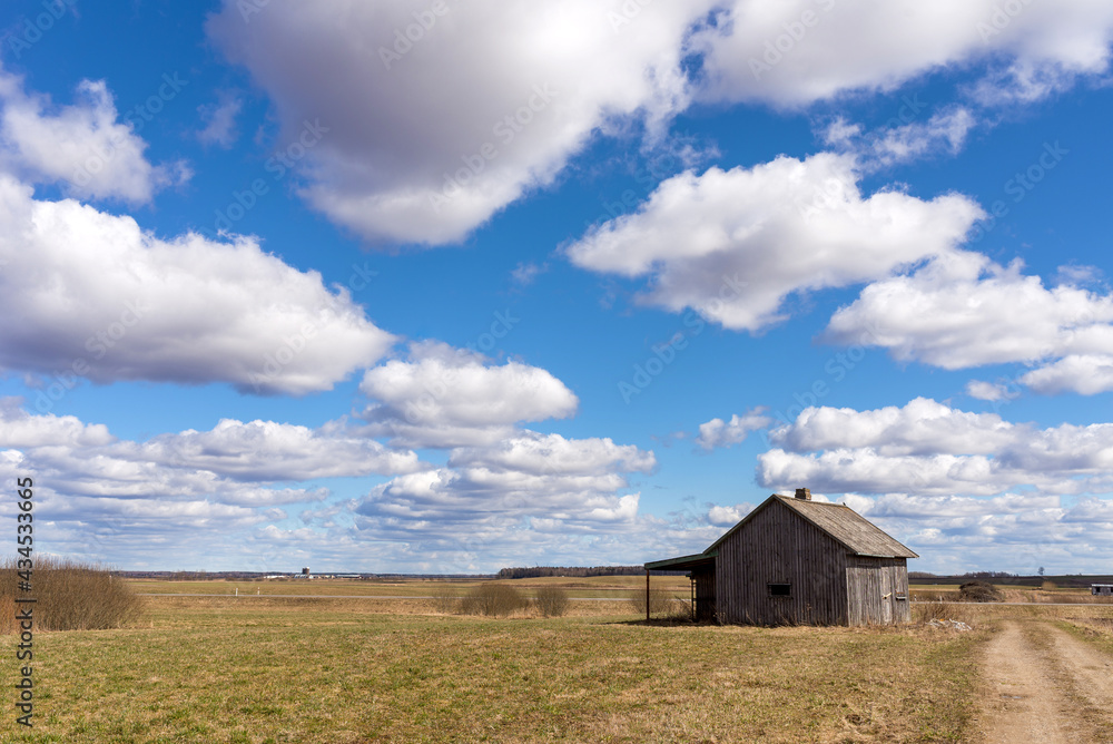 Fototapeta premium An old abandoned small wooden house in the fields sky clouds, barn or scary concept.
