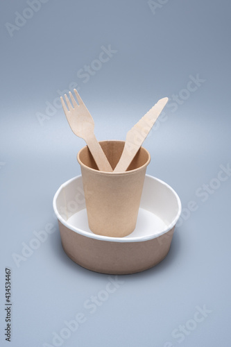 Wooden and cardboard disposable tableware on a gray background. Environmentally friendly products.