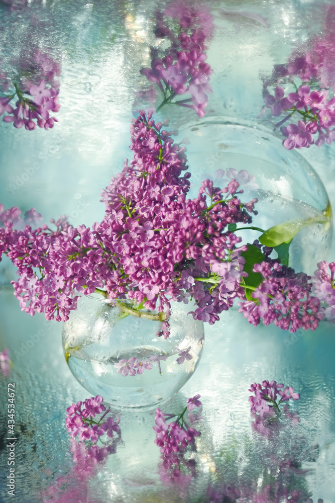 Obraz premium A bouquet of lilacs in a transparent vase. Artistic photo with sparkling bokeh and very soft selective focus. Shallow depth of field for an artistic idea. Spring bouquet.