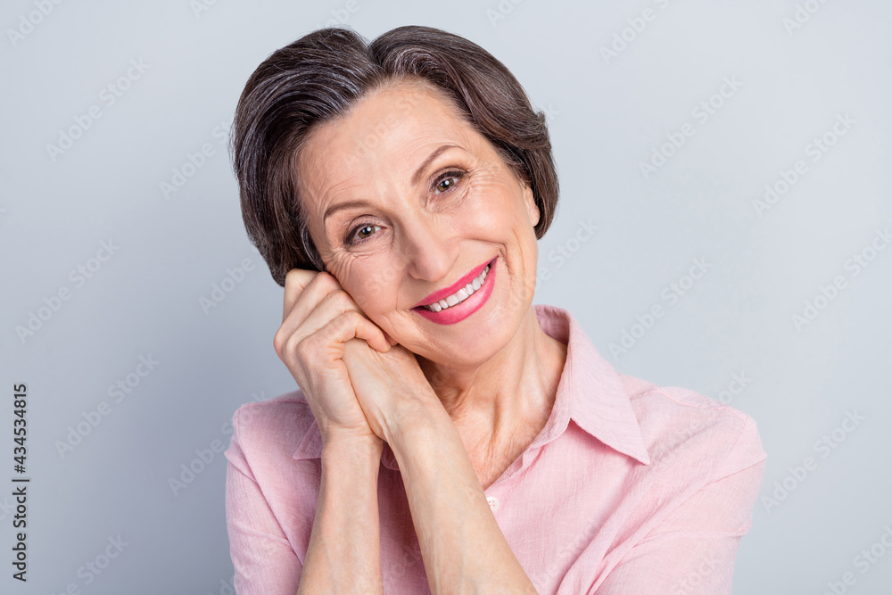 Photo of cute dreamy mature lady wear pink clothes smiling arms together cheek isolated grey color background Photo of cute dreamy mature lady wear pink clothes smiling arms together cheek isolated grey color background