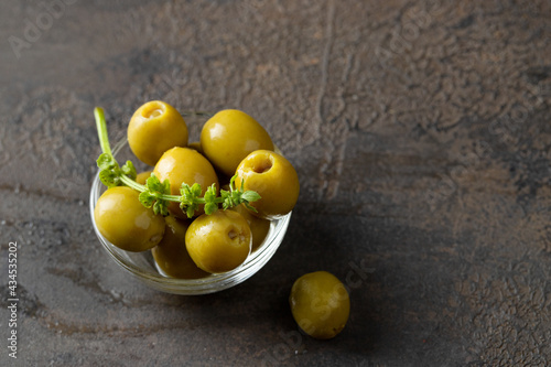 Green olives  on the bowl on dark concrete background.