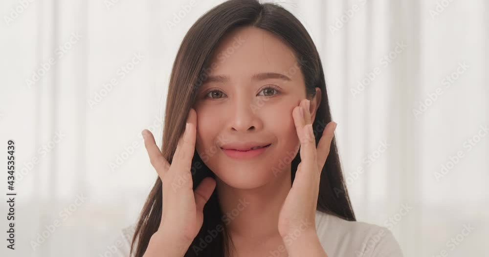 Portrait of Young Beautiful Woman looking to Camera with Smiling. She Massaging Her Face with Happy Emotion. Spa, Salon and Beauty Concept. Portrait of Young Beautiful Woman looking to Camera with Smiling. She Massaging Her Face with Happy Emotion. Spa, Salon and Beauty Concept.