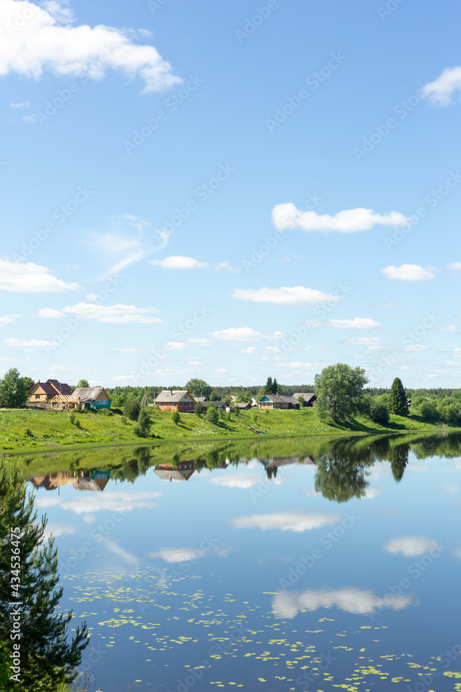 Beautiful rural landscape. Small village by the lake on a sunny summer day.